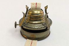 an antique brass bell with red thread on the top and white cord attached to it