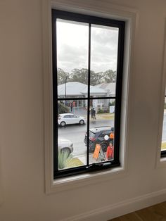 a window with cars parked in front of it and people walking on the street outside