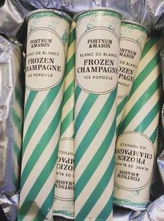 three green and white striped candles are in a tin foil bag with the words frozen champagne on it