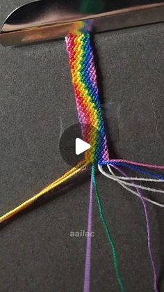 a pair of scissors are hooked up to some colorful thread and yarn on a table