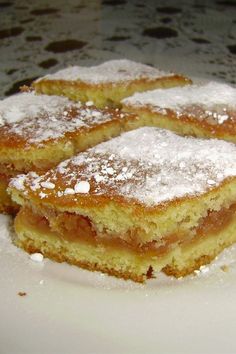 three pieces of cake sitting on top of a white plate covered in powdered sugar