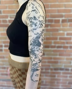 a woman with a tattoo on her arm is standing in front of a brick wall