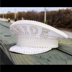 a white hat with the word bride written on it sitting on a wooden bench outside