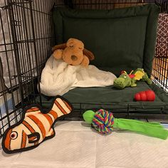 a stuffed animal laying on top of a bed in a cage next to other toys