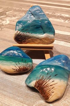 three hand painted rocks sitting on top of a table next to a tray with seaweed