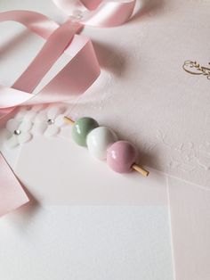 three candy lollipops sitting on top of a pink and white envelope with ribbon