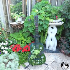 a guitar shaped planter sitting in the middle of a garden