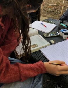 two people sitting at a table with notebooks and pens in their hands, writing on paper