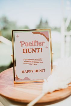 there is a sign that says happy hunt on the wooden table with white feathers in front of it