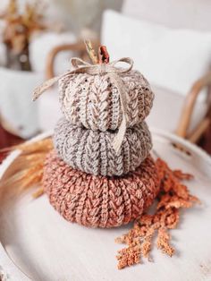 three knitted pumpkins are stacked on top of each other in the middle of a white plate