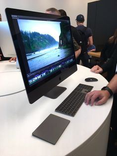 a man sitting in front of a computer on top of a white table next to a keyboard and mouse