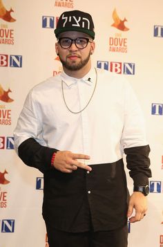 a man with glasses and a hat standing in front of a red carpet