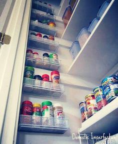 an open refrigerator door with canned food in the bottom shelf and labeled pantry storage below