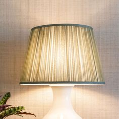 a white table lamp sitting on top of a wooden table next to a potted plant