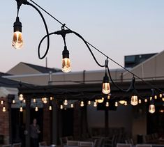 several light bulbs are hanging from a string on an outdoor dining room patio at dusk