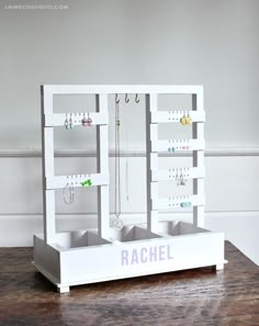 a jewelry rack with earrings and necklaces hanging from it's sides on a wooden table