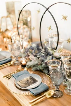 the table is set with silver and gold place settings, blue napkins, and star decorations