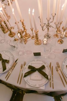 the table is set with gold and white place settings, silverware, and candles