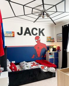 a child's bedroom with a spiderman theme on the wall