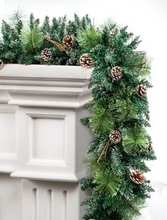 a white planter filled with pine cones and greenery