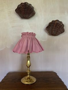 a lamp that is sitting on top of a wooden table next to two seashells