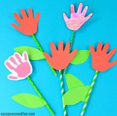 handprinted flowers made out of construction paper on a blue background with straws