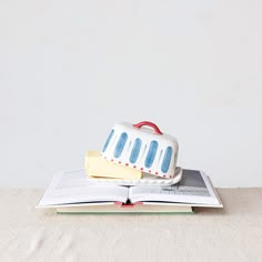 an open book sitting on top of a wooden table next to a white and blue cake