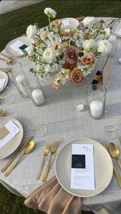 the table is set with gold and white plates, silverware, and floral centerpieces