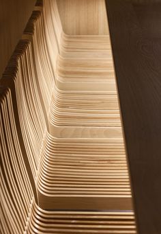 a close up of a wooden bench made out of strips of plywood planks