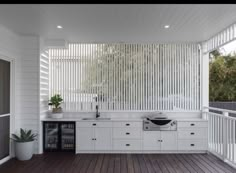 an outdoor kitchen with wooden floors and white walls