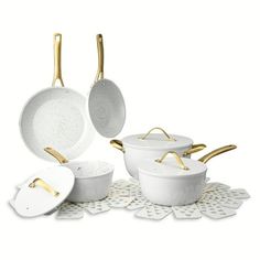 an assortment of white pots and pans with gold handles