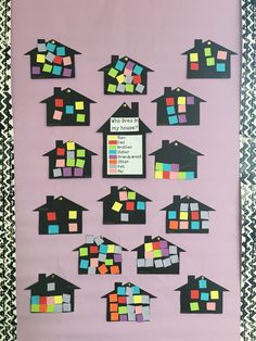 a bulletin board with different colored squares and houses on it's sides, in front of a pink wall