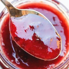 a spoon full of strawberry jam sitting in a jar