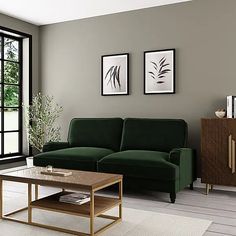 a living room with green couches and two pictures on the wall above it's coffee table