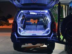 the back end of a vehicle with its cargo compartment open and lights on at night