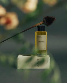 a bottle of cologne sitting on top of a white box next to a brown brush