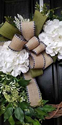 a wreath with white flowers and greenery tied to it