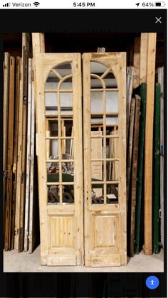 two wooden doors sitting next to each other in front of stacks of wood planks