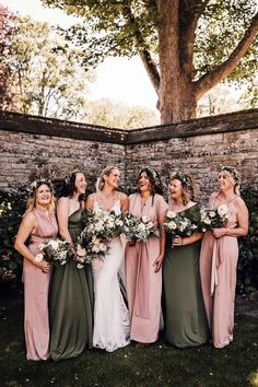 a group of women standing next to each other wearing dresses and holding bouquets in their hands