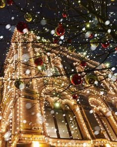 christmas lights are hanging on the side of a building in front of a clock tower