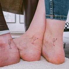 two people with matching tattoos on their feet, one is holding a wine glass and the other has an umbrella