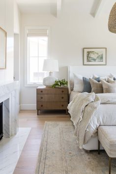 a white bed sitting next to a fireplace in a bedroom