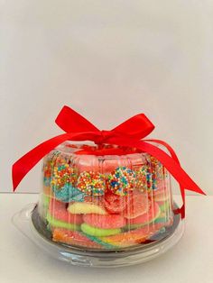 a cake covered in lots of colorful candies and sprinkles with a red ribbon