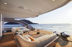 the inside of a boat with couches and tables on it's deck overlooking the water