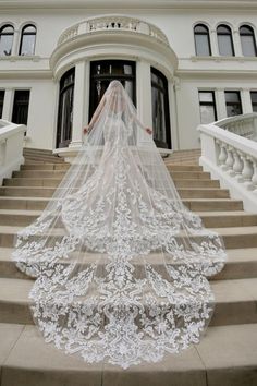 a woman in a wedding dress standing on some steps with a veil over her head