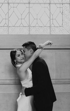 a bride and groom kissing in front of a wall