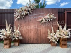 an outdoor ceremony setup with flowers and feathers on the back wall, in front of a wooden fence