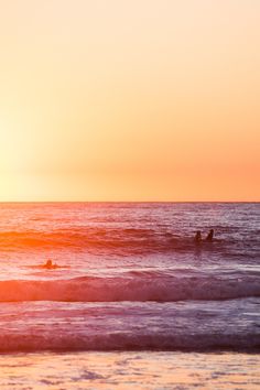 two surfers in the ocean at sunset