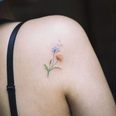 the back of a woman's shoulder with a flower tattoo on her left side