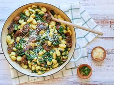 a skillet filled with pasta, mushrooms and spinach